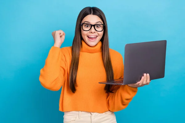 照片上 一个快乐的女孩穿着长发 头戴针织套头衫 带着笔记本电脑 在蓝色背景下通过了考试 — 图库照片