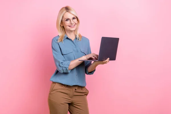 Photo portrait of happy professional freelance accountant mature smiling woman hold netbook work remote web job isolated on pink color background.