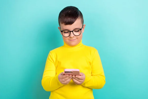Photo of kid boy using smart gadget reading facebook posts isolated on cyan blue color background.
