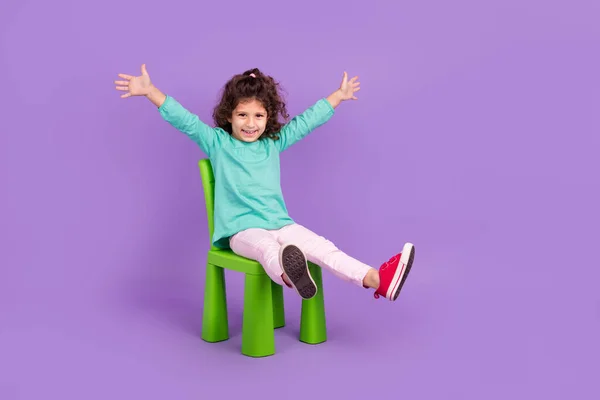 興奮したファンキーな小さな子供の完全な長さの写真は ターコイズシャツ座って椅子上昇手腕空のスペース孤立紫色の背景 — ストック写真