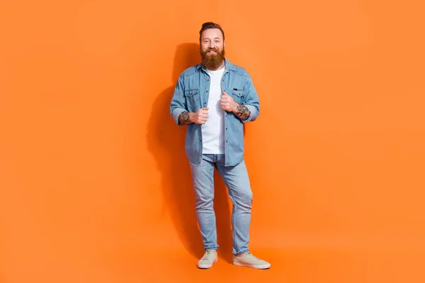 Full body photo of brutal masculine young irish hipster guy wear denim stylish outfit posing model shopping promo isolated on orange color background.