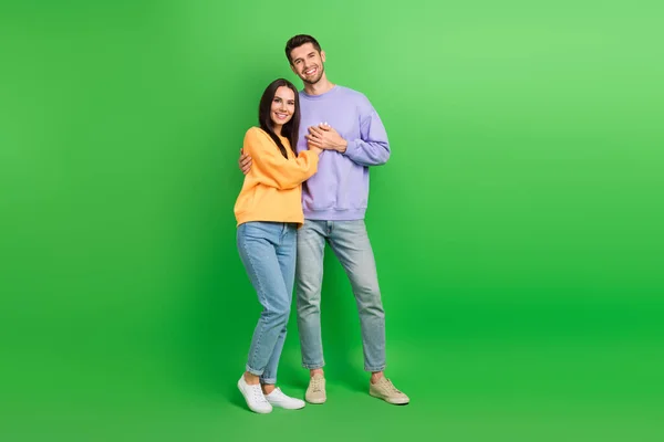 全长照片 漂亮闪亮的丈夫妻子穿着运动衫 抱着孤零零的绿色背景 — 图库照片