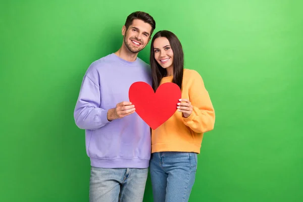 两个和平可爱的伴侣手挽着绿颜色背景的纸制心脏卡微笑着拥抱在一起的照片 — 图库照片