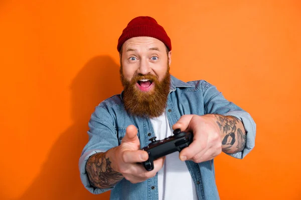 面白い若い男の写真赤い髪のひげは 無線ジョイスティッククレイジーサイバープレーヤービデオゲームは オレンジの色の背景に孤立楽しい時間を持っています — ストック写真