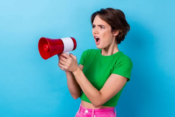 Photo of angry serious lady dressed green top shouting loudspeaker empty space isolated blue color background.