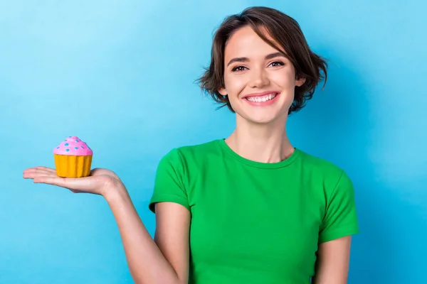 面白い陽気な女性の写真緑のトップ保持アーム小さなカップケーキ孤立青の色の背景を身に着けている — ストック写真