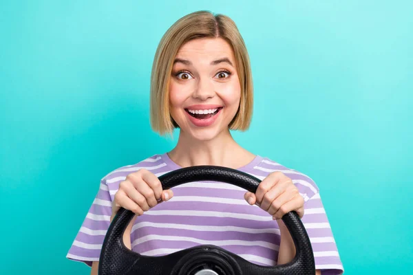 Photo of impressed ecstatic girl striped t-shirt sunglass hold steering wheel astonished staring isolated on turquoise color background.