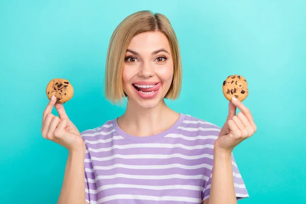 フレンドリーなかわいい女性の写真とともにボブ ヘアドレスストライプのTシャツホールドクッキー舌なめる歯の色の背景に隔離 — ストック写真
