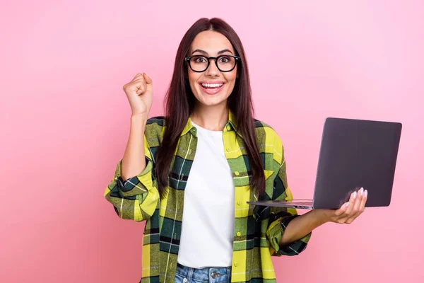 楽観的な恍惚の少女のストレートヘアスタイルの写真チェックされたシャツを保持ノートパソコンの勝利宝くじピンク色の背景に孤立 — ストック写真