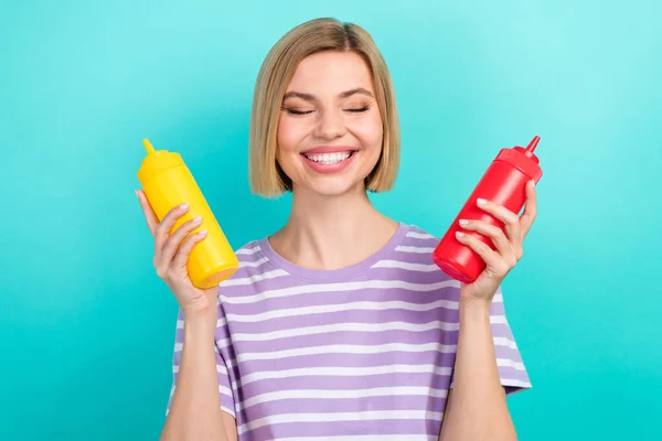 Photo of cheerful funny person bob hairdo trendy t-shirt cooking burger hold bottles of ketchup isolated on turquoise color background.