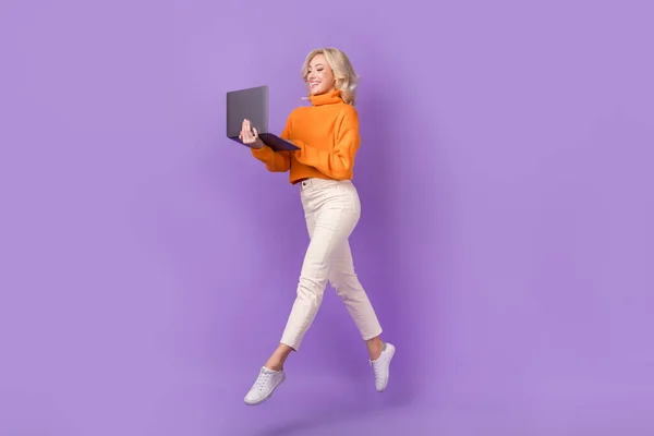 Full length profile photo of active pretty person jumping use netbook isolated on violet color background.