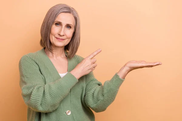 自信を持って年金生活者の女性の写真は スタイリッシュなシャツを着用アームポイント指の目新しさオプションWebサービスベージュの色の背景に隔離 — ストック写真