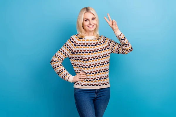 Photo of excited charming lady dressed pullover showing v-sign smiling isolated blue color background.