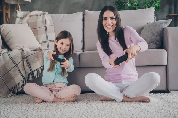 stock image Photo of positive cheerful family mommy kid girl playing console joy stick sit carpet in modern apartment flat.