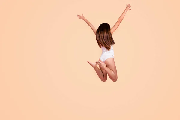 Rear behind back view full length size body of young gorgeous nice straight-haired lady wearing sleepwear, jumping in air. Isolated over pink pastel background.