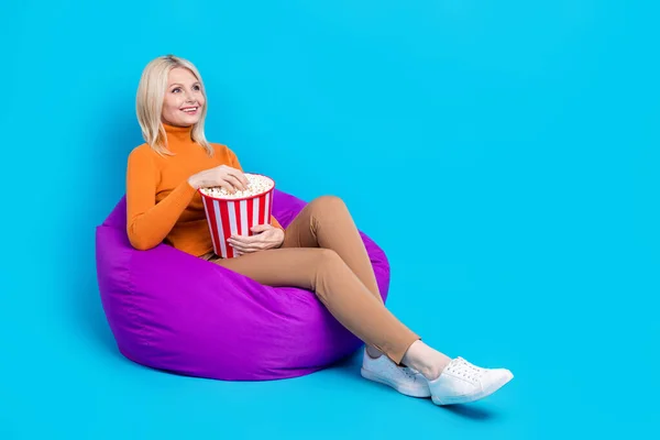 フルサイズの写真の良い気分陽気な女性着用オレンジTurtleeck座って上のPoufお楽しみください素晴らしい映画孤立した青の色の背景 — ストック写真