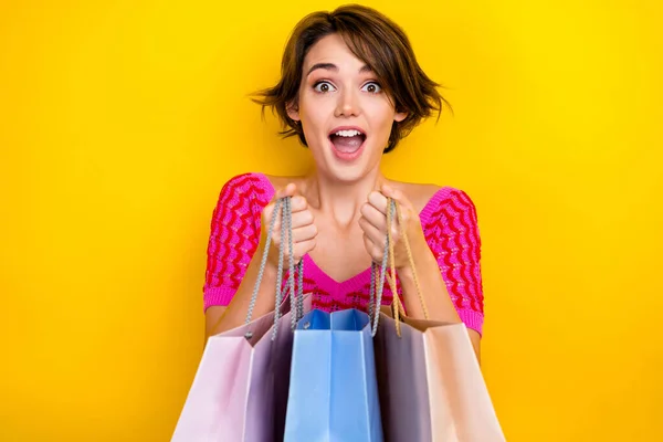 年轻女孩惊讶地在购物袋里猜到 生日宴会上的新衣服是用黄色背景隔开的 照片上有她的购物袋里卖广告礼物 — 图库照片