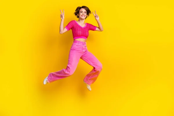 屈託のないエネルギッシュな女性の若いジャンプの完全な長さボディ幹部は楽しいショーVサイン挨拶シンボルが黄色の色の背景に隔離されている — ストック写真