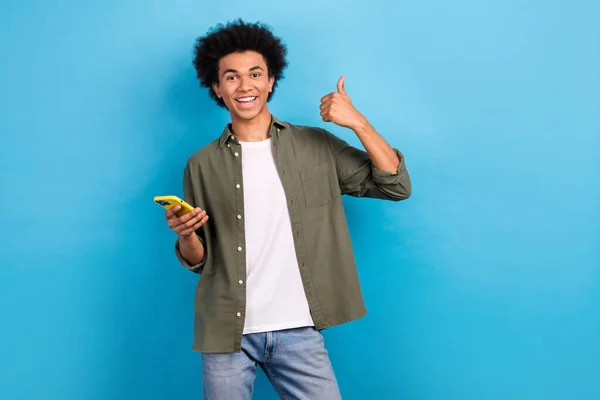 年轻快乐的小伙子享受他的新苹果Iphone大拇指上升率推荐快速界面隔离在蓝色背景下的照片 — 图库照片