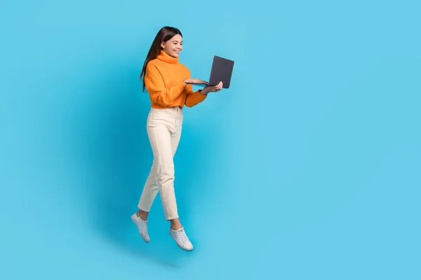 stock image Full size portrait of carefree cheerful girl hold use netbook jump empty space isolated on blue color background.