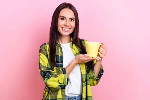 楽観的な優しい女性の肖像ブルネットの髪はピンクの色の背景に孤立したヤシの上にコーヒーのカップを保持黄色のジャケットを身に着けている — ストック写真