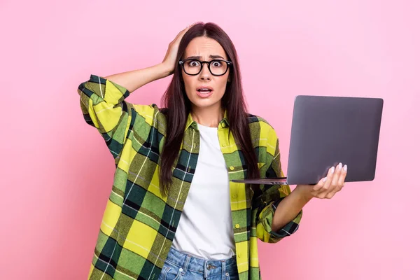 Portrait of stressed confused person long hairstyle wear yellow jacket arm on head hold laptop staring isolated on pink color background.