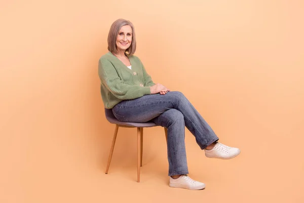 居心地の良い座っているシニア女性のフルボディ写真白い髪新しい家具の椅子プロモーション広告ビルボード広告ベージュ色の背景に隔離 — ストック写真