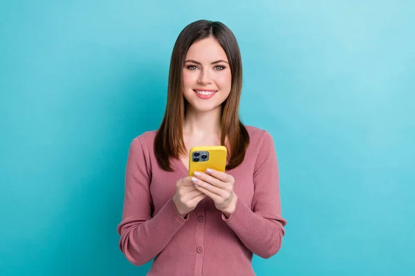 明るい気分の女の子の写真とともにまっすぐヘアドレスピンクカーディガン保持スマートフォン読み取りポスト青の色の背景に隔離 — ストック写真
