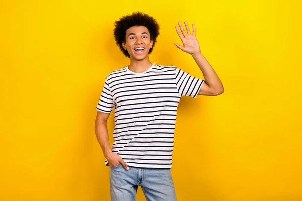 写真のポートレート面白い学生男良い気分波の腕こんにちは友人は ストライプのTシャツのジーンズを着用していると言う黄色の背景を隔離 — ストック写真