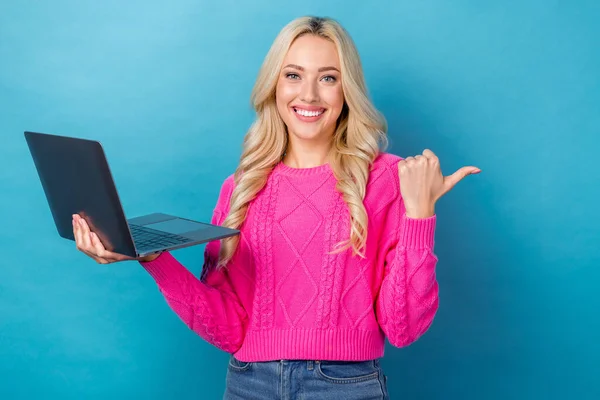 穿着粉色套头衫 开朗可爱的女人的画像 手持笔记本电脑 将空旷的空间分隔在蓝色的背景下 — 图库照片