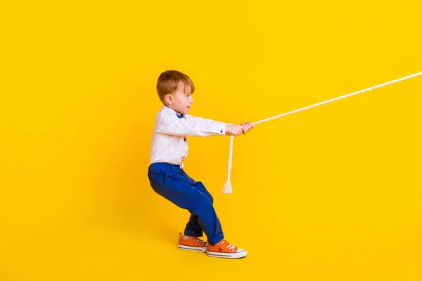 プロフィール側フルボディ写真の小さな男の子感じ強い完全なチャレンジ綱引き孤立上の明るい色の背景 — ストック写真