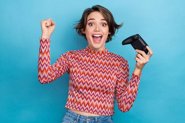 stock image Photo portrait of pretty young girl hold joystick win playstation raise fist wear trendy striped outfit isolated on blue color background.