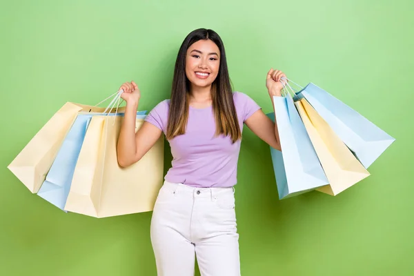 美しい日本人の若い女性の写真ショッピングバッグを保持買い物客は緑の色の背景に隔離された流行の紫色の服を身に着けている — ストック写真