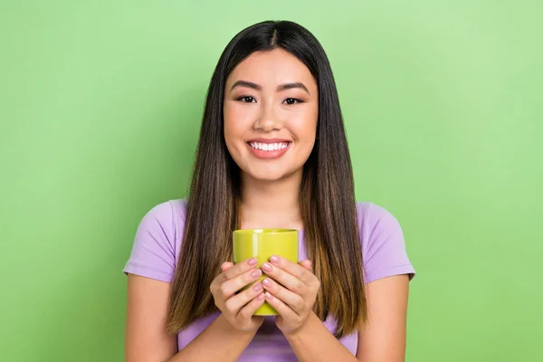 Photo portrait of pretty japanese korean young girl hold tea coffee mug smile wear trendy purple outfit isolated on green color background.