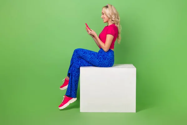 フルサイズプロフィール写真の美しい陽気な女の子座って表彰台使用スマートフォン隔離上の緑の色の背景 — ストック写真