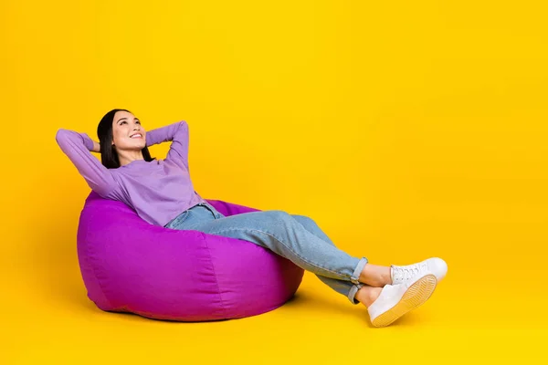 中国女孩穿着紫色衬衫斜纹棉布牛仔裤睡午觉休息手头豆袋隔离在黄色背景下的全身照片 — 图库照片