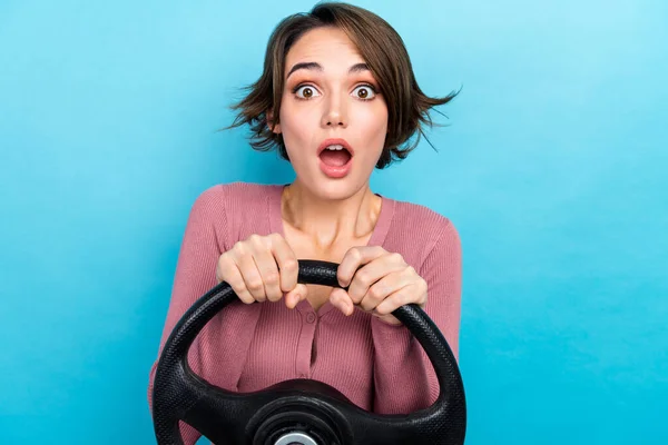 年轻女子身穿粉色衬衫手持方向盘驾驶模拟器的照片 在蓝色背景下做出意想不到的反应 — 图库照片