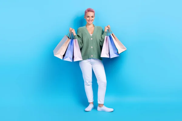 若いモデルの全身写真ピンク色の髪の毛の女性は 青の色の背景に隔離された新しいスニーカー店から袋を保持緑色のシャツを身に着けている — ストック写真