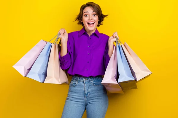 迷人的年轻女子手持购物袋 穿着时尚的紫色智能休闲装 与黄色背景隔离的照片肖像 — 图库照片
