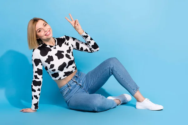 若い女性の完全な長さ写真ボブ髪ショーVサイン座っている牛の皮作物トップ平和のシンボルは 青の色の背景に隔離された — ストック写真