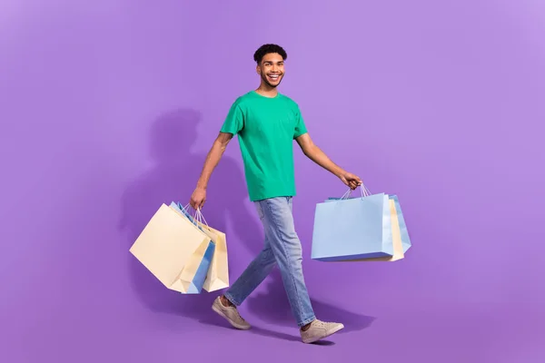 若い男の完全な体の長さの幹部歩くとともにショッピングパッケージバッグ店内バイヤー隔離された紫色の背景 — ストック写真