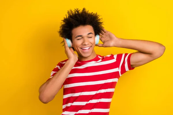 남자가 티셔츠를 이어폰으로 노래를 노란색 배경을 고립시켰다 — 스톡 사진