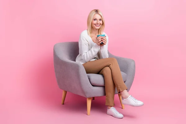 満足素敵な女性のフルサイズ写真座って居心地の良い椅子ホールドホットチョコレートカップピンク色の背景に隔離 — ストック写真