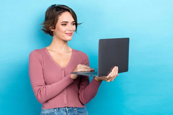 图片上的可爱的积极聪明的女人 身穿粉色毛衣 头戴短发 看起来像笔记本电脑 背景是单色的 — 图库照片