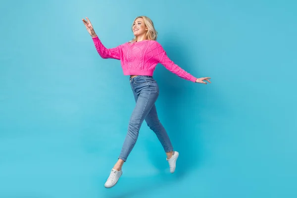 フルボディサイズ幹部の若いです美しいです女性着用ピンクセーター実行しているジャンプステップ不注意な快適さで青の色の背景に隔離 — ストック写真