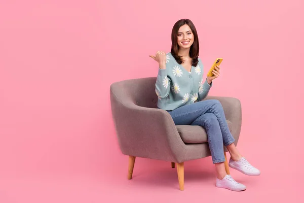 フルボディ長さCadreの若いです女性着用ジャンパー座って快適椅子ポイント指便利なヒントMokup隔離されたピンク色の背景 — ストック写真