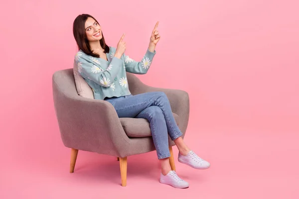 フルボディCadreの若いです満足女性座って灰色の椅子お勧めポイント指見える空のスペースでピンク色の背景 — ストック写真