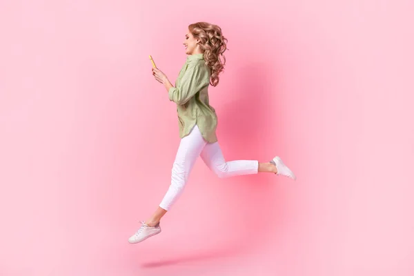 フル長さ写真のファンキーな光沢のある女性着用グリーンシャツ通信現代ガジェットジャンプ高絶縁ピンク色の背景 — ストック写真