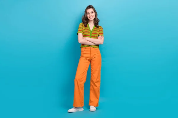 フルサイズの写真の良い気分素敵な女性服オレンジ色のパンツカラフルなカーディガン立って腕の青の色の背景に孤立折り畳まれた — ストック写真