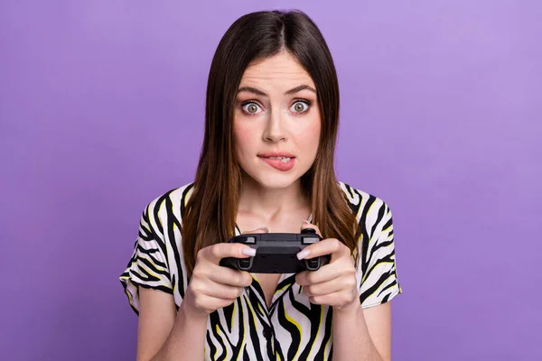 Portrait of excited nervous person biting lips hands hold controller play video games isolated on purple color background.